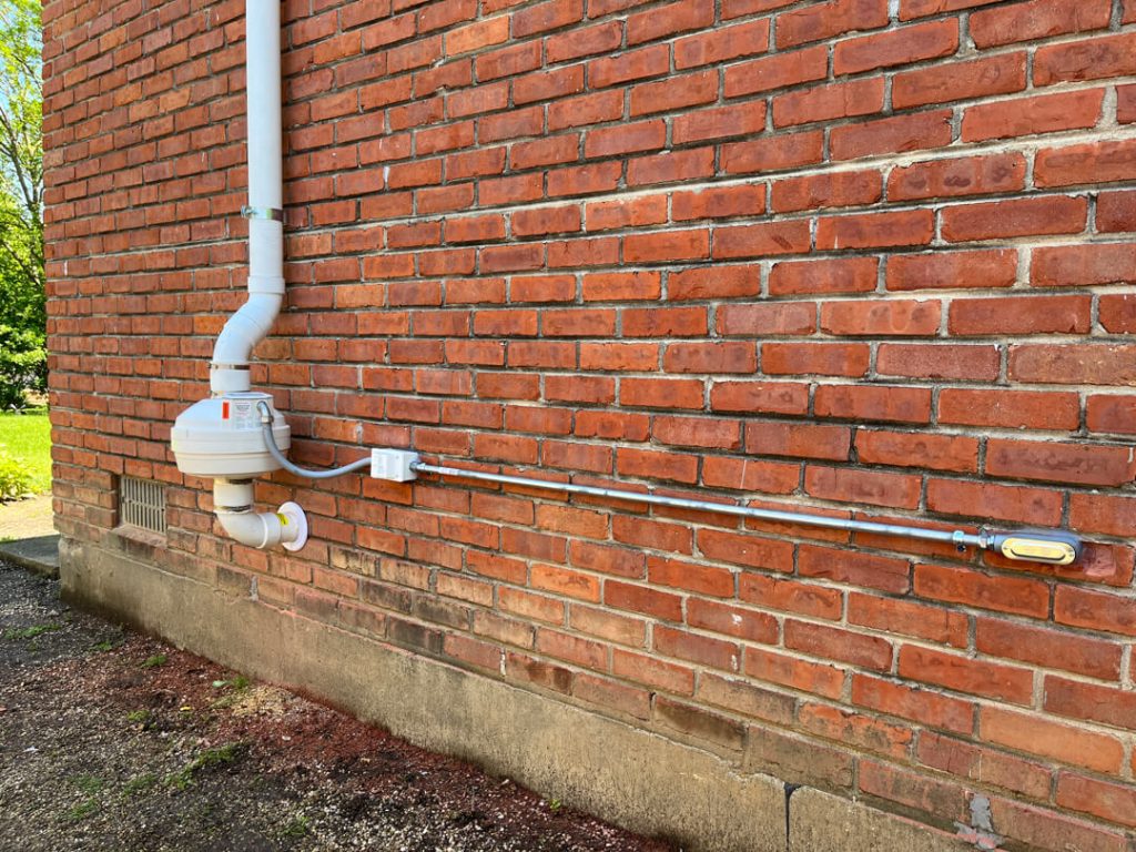 Radon mitigation system on brick house exterior