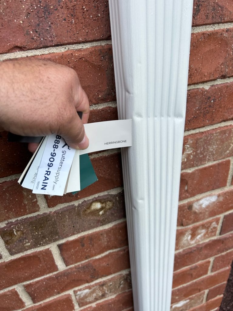 Man Inspecting House Downspout for Residential Radon Mitigation Project For Color Sampling For Radon Mitigation System Coloring