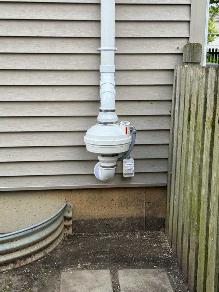Radon mitigation system installed on house exterior
